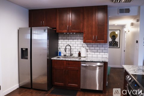 A kitchen with a stainless steel refrigerator and wooden cabinets.