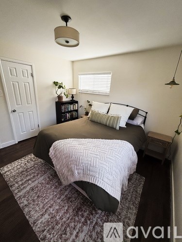 A bedroom with a bed and a rug on the floor.