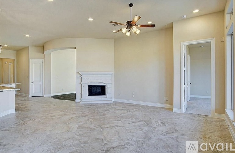 A spacious living room with a fireplace and a ceiling fan.