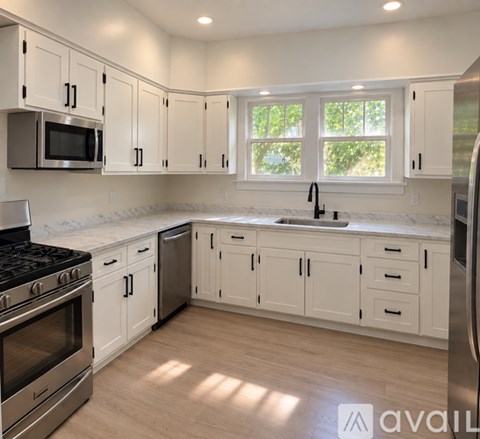 A kitchen with white cabinets and a stainless steel refrigerator.