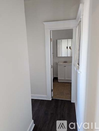 A white bathroom with a mirror and a cabinet.