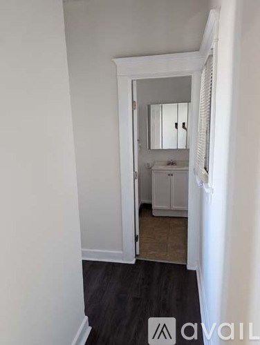 A white bathroom with a mirror and a cabinet.