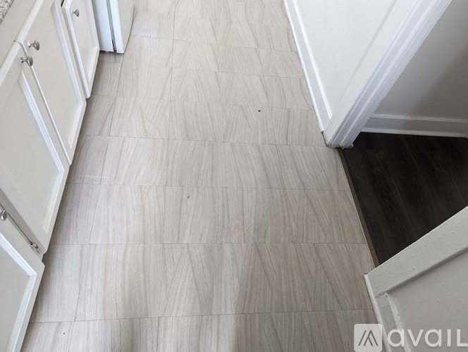 A kitchen with white cabinets and a wooden floor.