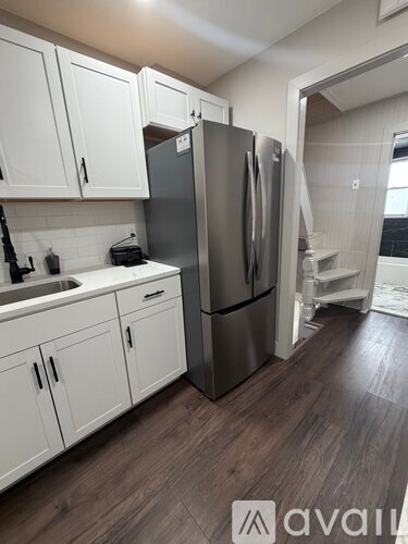 A kitchen with white cabinets and a stainless steel refrigerator.