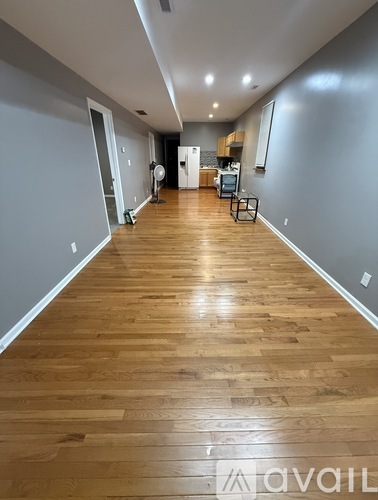 A long hallway with wooden floors and a kitchen area in the distance.