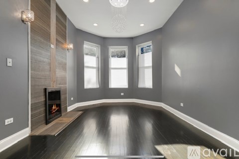 A spacious room with a fireplace and wooden floors.