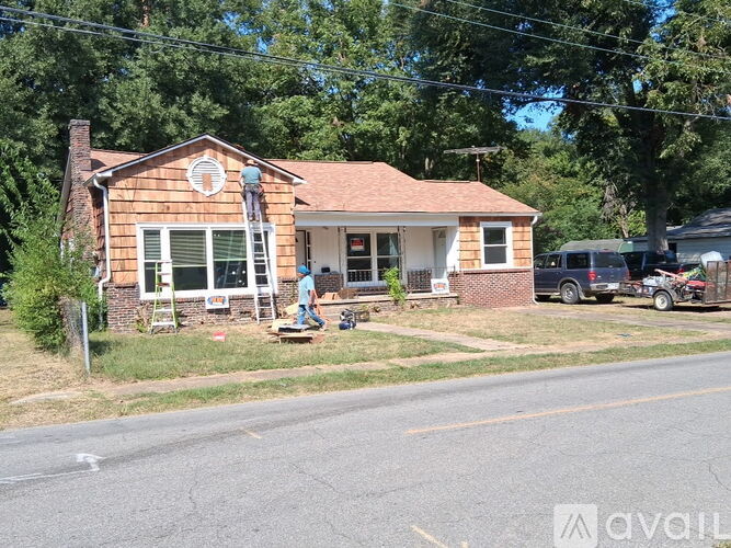 A house with a brown roof and a white door is surrounded by trees.