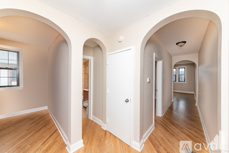 A spacious room with wooden floors and arched doorways.