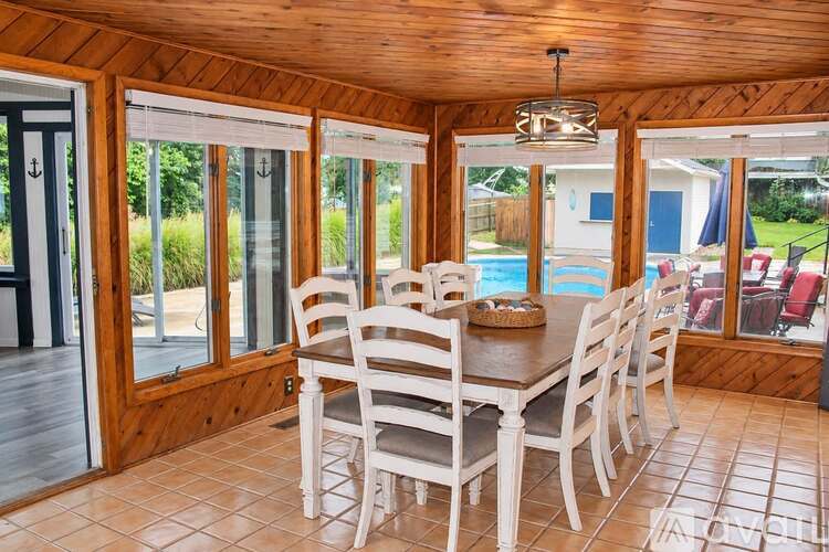A dining room with a table and chairs and a pool in the background.