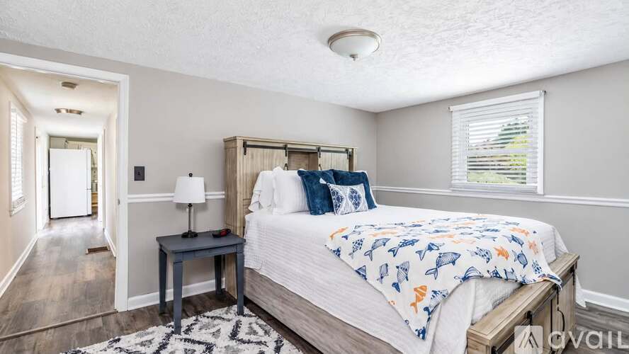 A bedroom with a bed, nightstand, and window.