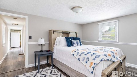 A bedroom with a bed, nightstand, and window.