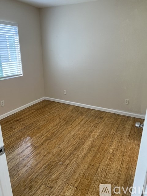A room with wooden flooring and a window with blinds.