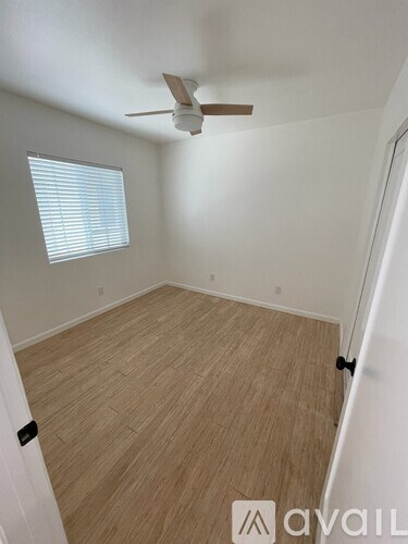 A room with a ceiling fan and a window with blinds.