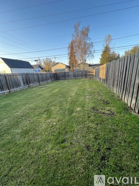 A backyard with a wooden fence and a grassy area.