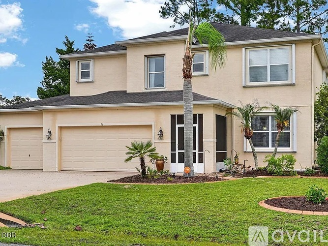 A two-story house with a garage and palm trees in front.