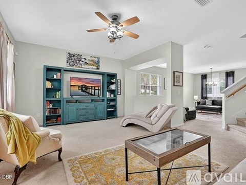 A living room with a yellow chair and a glass coffee table.