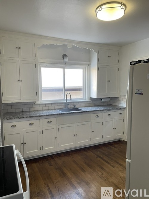A kitchen with white cabinets and a window over the sink.