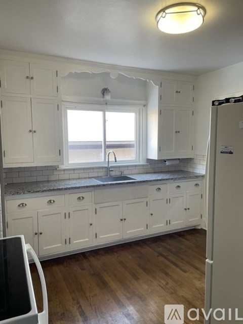 A kitchen with white cabinets and a window over the sink.