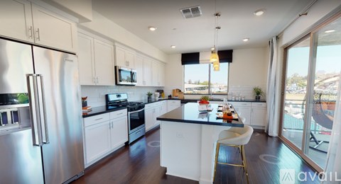 A modern kitchen with a refrigerator, stove, and a dining area with a table and chairs.