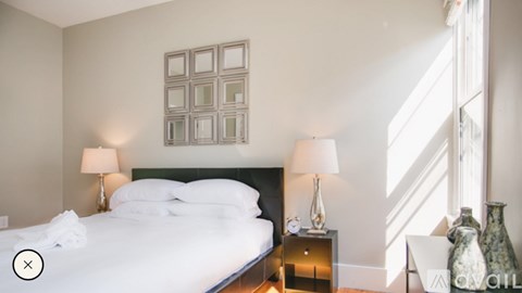 A bedroom with a large bed and a lamp on a nightstand.