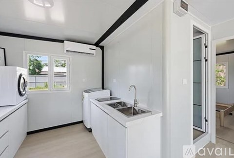 A white kitchen with a sink, dishwasher, and refrigerator.