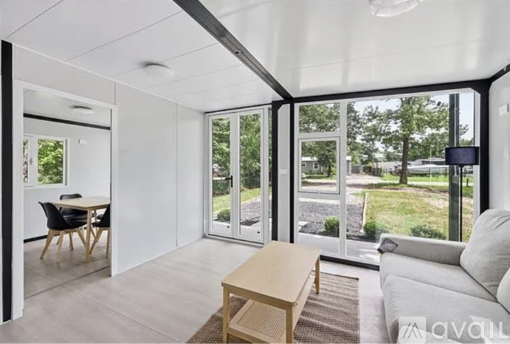 A modern living room with a dining area and a view of the backyard.