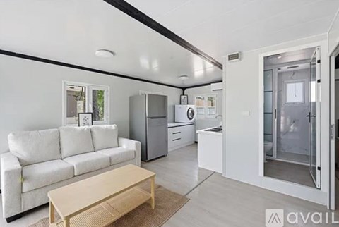 A modern kitchen with white appliances and a white couch.