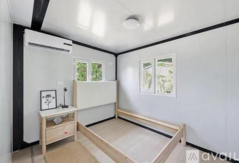 A room with a bed, desk, and window.
