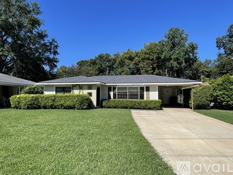 A house with a well-maintained lawn and trees in the background.