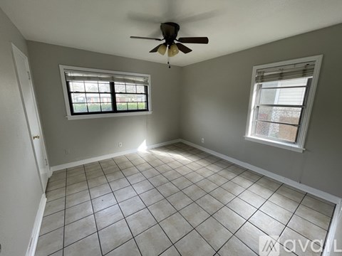 A room with a ceiling fan and two windows.