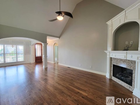 A spacious room with a fireplace and a ceiling fan.