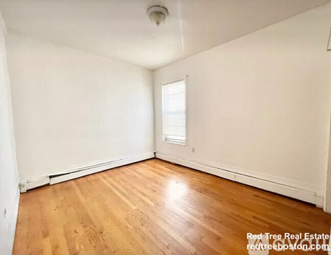 A room with wooden flooring and a window.