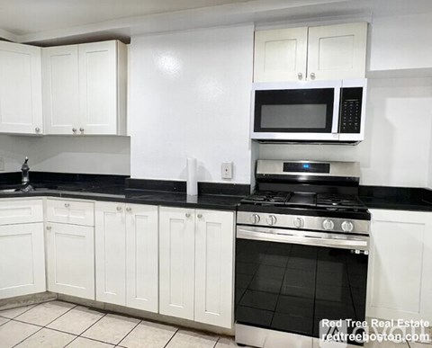 A kitchen with white cabinets and black countertops.