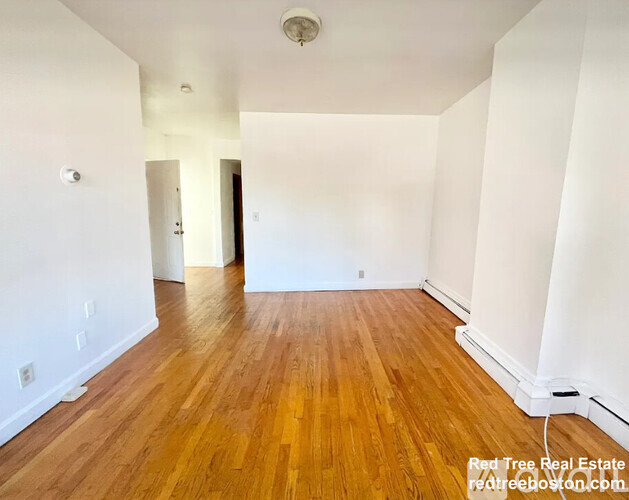 A room with wooden flooring and white walls.