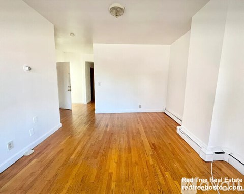 A room with wooden flooring and white walls.