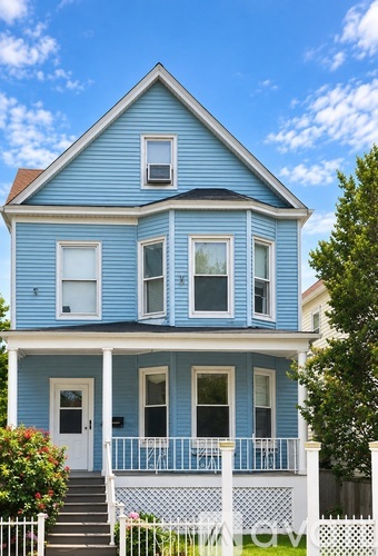 A blue house with white railings and a white picket fence.