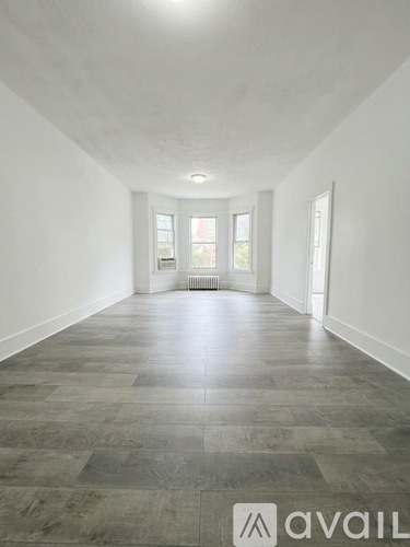A spacious room with grey tiled flooring and white walls.
