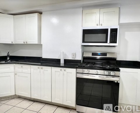 A kitchen with white cabinets and black countertops.