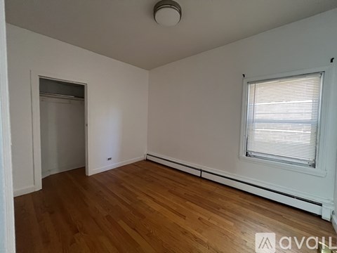 A room with wooden floors and a window with blinds.