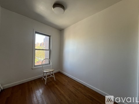 A room with a wooden floor and a window with a chair in it.