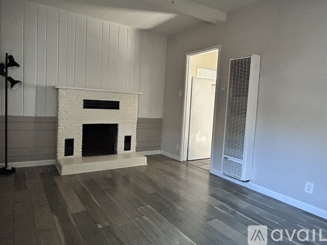 A white fireplace in a room with wooden flooring and white walls.