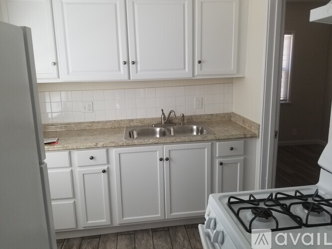 A kitchen with white cabinets and a white gas stove.