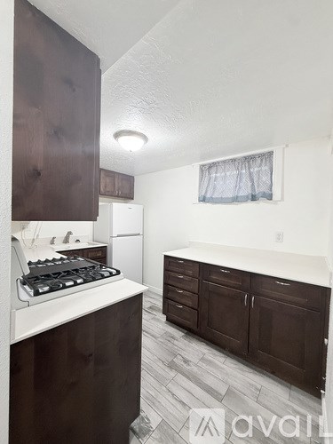 A kitchen with a white counter top and dark wood cabinets.