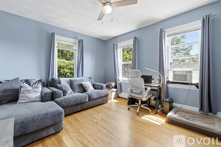 A living room with a grey couch and a desk with a chair.