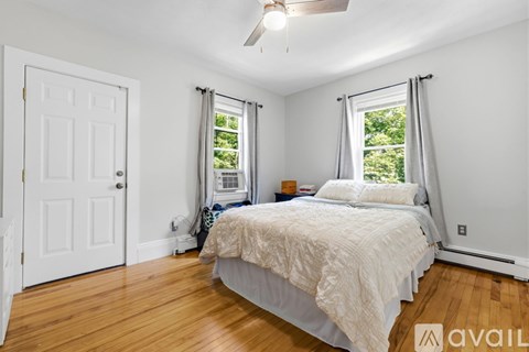 A bedroom with a bed, a window with curtains, and a ceiling fan.