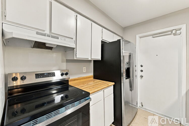 A kitchen with a black refrigerator and stove top oven.