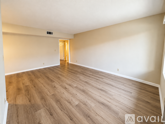 A room with wooden flooring and a doorway leading to another room.