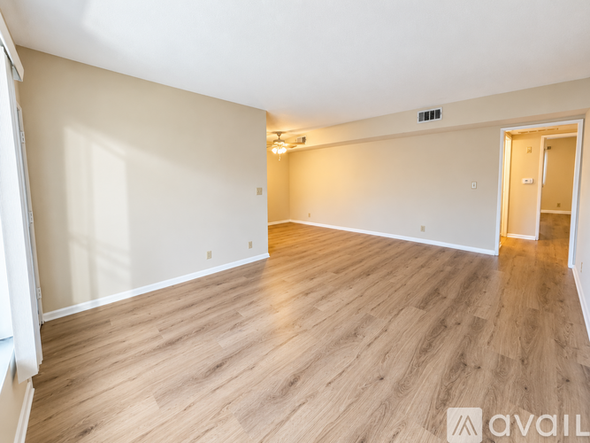 A spacious room with wooden flooring and a door on the right side.