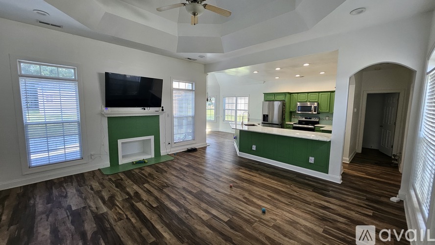 A living room with a television and a green kitchenette.
