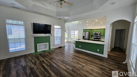 A living room with a television and a green kitchenette.